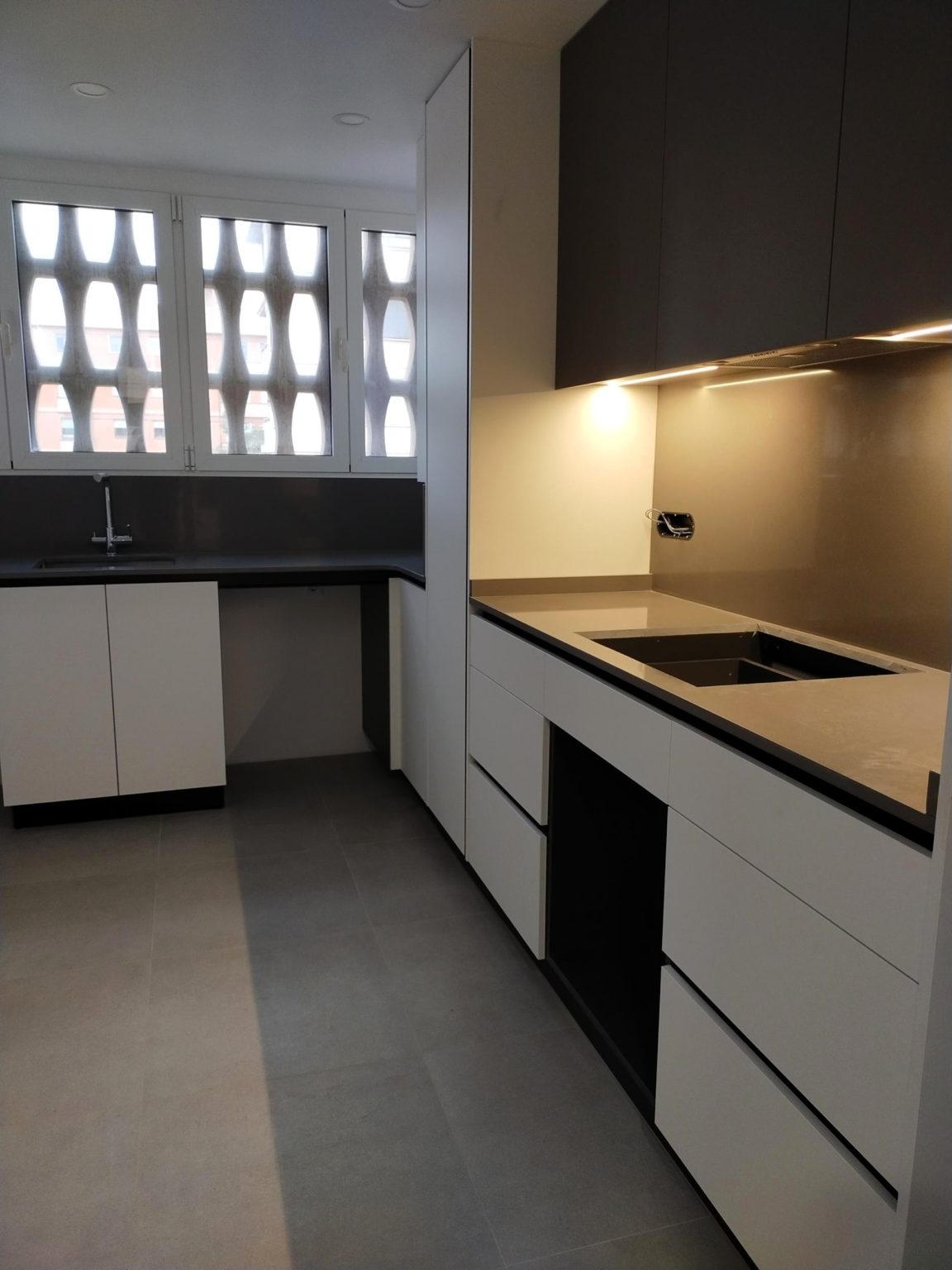 Cocina a medida en Castellón con muebles blancos y encimera negra realizada por Carpintería Pablo Celades