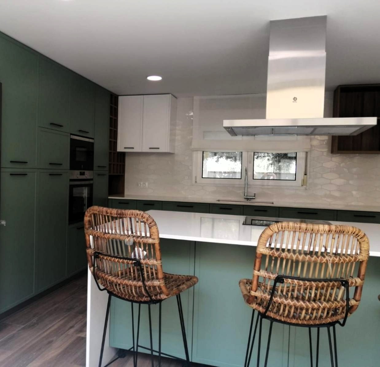 Cocina personalizada en Castellón con muebles verdes, barra y taburetes de madera