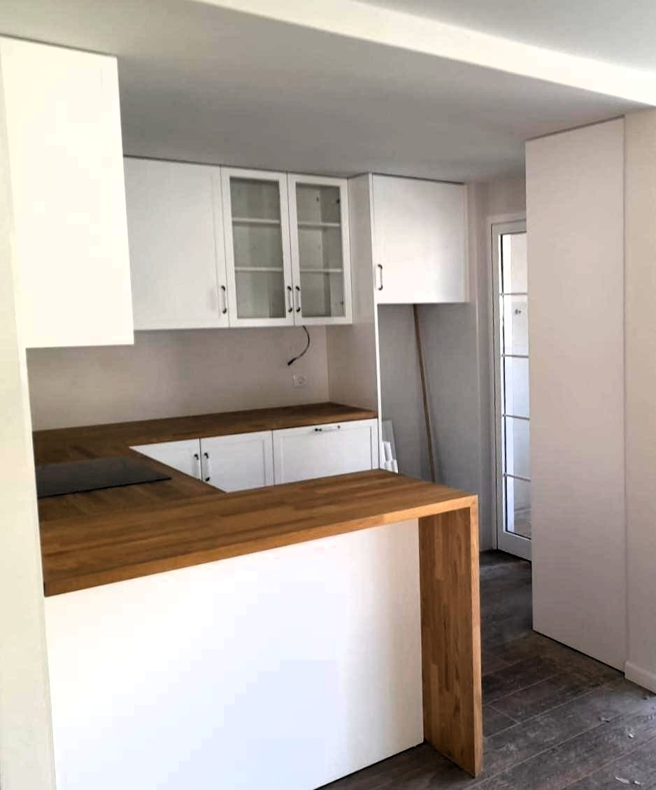 Cocina a medida en Castellón con encimera de madera, muebles blancos y península personalizada